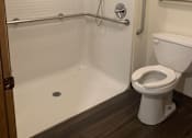 Thumbnail 6 of 6 - A white toilet is mounted above a white bathtub with a shower head.
