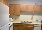 Thumbnail 5 of 6 - A white fridge in a kitchen with wooden cabinets.