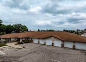 Thumbnail 14 of 14 - A parking lot in front of a building with a brown roof.