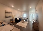 Thumbnail 4 of 14 - A living room with a couch, a coffee table, and a painting on the wall.