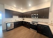 Thumbnail 5 of 14 - A modern kitchen with dark brown cabinets and stainless steel appliances.