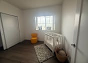 Thumbnail 8 of 14 - A baby room with a white crib and a yellow ottoman.