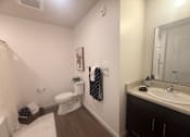 Thumbnail 11 of 14 - A bathroom with a toilet, sink, and mirror.