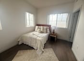 Thumbnail 6 of 14 - A bedroom with a bed, a small table, and a rug.