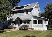 Thumbnail 5 of 5 - A two-story house with a front porch and a small front yard.