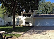 Thumbnail 4 of 5 - A house with a white garage door and a tree in front.