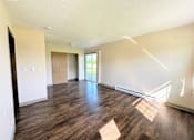 Thumbnail 8 of 21 - an empty living room with wood floors and white walls