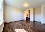 Thumbnail 9 of 21 - an empty living room with hard wood floors and white walls