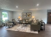 Thumbnail 16 of 21 - A living room with a grey couch, two chairs, a coffee table, and two framed pictures on the wall.