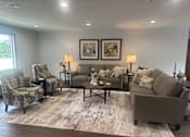 Thumbnail 18 of 21 - A living room with a grey sofa, two chairs, and a coffee table.