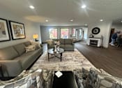Thumbnail 20 of 21 - A living room with a grey couch, a coffee table, and a fireplace.