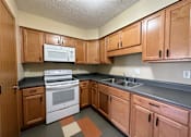 Thumbnail 6 of 10 - a kitchen with wood cabinets and white appliances