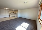 Thumbnail 3 of 13 - an empty living room with a kitchen in the background