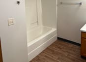 Thumbnail 9 of 12 - A white bathroom with a shower and a white wall.