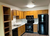 Thumbnail 4 of 12 - A modern kitchen with wooden drawers and black appliances.