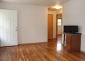 Thumbnail 7 of 11 - A room with a white door, a brown cabinet, and a wooden floor.