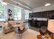 Thumbnail 3 of 22 - A modern living room with a couch, coffee table, and a kitchen area in the background.