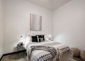 Thumbnail 10 of 22 - A bedroom with a bed, a lamp, and a wall hanging.