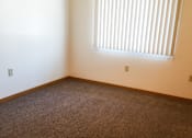 Thumbnail 8 of 12 - A room with a carpeted floor and a window with blinds.