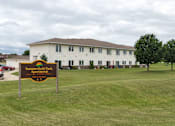 Thumbnail 1 of 12 - A sign for Summerfield Park Apartments stands in front of a white building.