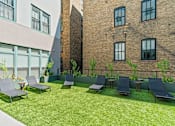 Thumbnail 43 of 45 - Courtyard with grills, lounge chairs, bocce ball, grass, and greenery at The Cosmopolitan, St Paul, MN, Minnesota, 55101