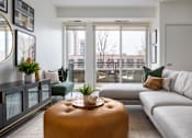 Thumbnail 4 of 22 - A living room with a grey couch, a brown ottoman, and a green chair.