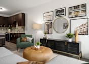 Thumbnail 6 of 22 - A living room with a grey sofa, a green armchair, a wooden coffee table, and a wall with framed pictures.