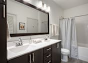 Thumbnail 9 of 22 - A bathroom with a white sink and a white toilet.