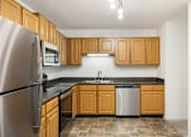 Thumbnail 6 of 45 - an empty kitchen with wooden cabinets and stainless steel appliances at Cityscape, St Louis Park, MN, 55416