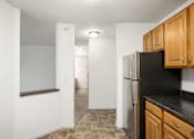 Thumbnail 7 of 45 - an empty kitchen with a refrigerator and wooden cabinets at Cityscape, St Louis Park, Minnesota