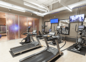 Thumbnail 12 of 25 - a gym with several treadmills and weights and a tv  at The Cosmopolitan, Minnesota, 55101