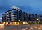 Thumbnail 21 of 22 - A modern building with a curved top is illuminated at night.