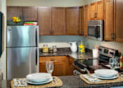 Thumbnail 1 of 26 - A kitchen with a refrigerator, microwave, and oven.