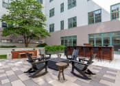 Thumbnail 22 of 25 - an outdoor patio with tables and chairs and a building in the background at The Cosmopolitan, St Paul