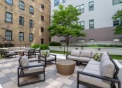 Thumbnail 23 of 25 - an outdoor patio area with couches and tables and a brick building  at The Cosmopolitan, St Paul, Minnesota