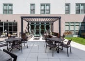 Thumbnail 24 of 25 - an outdoor patio with tables and chairs and a building in the background  at The Cosmopolitan, St Paul, MN, 55101