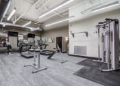 Thumbnail 15 of 25 - a gym with cardio equipment and weights in a building with white walls  at The Cosmopolitan, St Paul, Minnesota