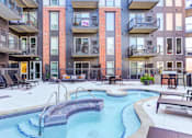 Thumbnail 20 of 22 - A pool with a metal railing is surrounded by chairs and tables.