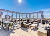 Thumbnail 18 of 22 - A sunny day on a rooftop patio with tables and chairs.