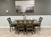 Thumbnail 10 of 19 - A wooden dining table with four chairs and a painting on the wall.