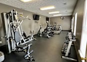 Thumbnail 12 of 19 - A gym with a variety of equipment including weights and cardio machines.