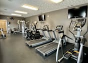 Thumbnail 13 of 19 - A gym with treadmills, elliptical machines, and other exercise equipment.