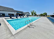 Thumbnail 31 of 49 - A large outdoor swimming pool with a diving board and lounge chairs.