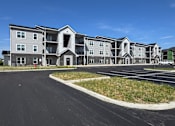 Thumbnail 35 of 57 - A large apartment complex with a parking lot in front.