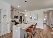 Thumbnail 5 of 20 - A kitchen with a white island and brown bar stools.