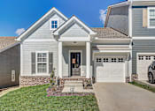 Thumbnail 1 of 20 - A house with a grey exterior and a white garage door.