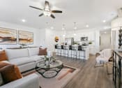 Thumbnail 6 of 25 - a living room with a couch and a table in front of a kitchen