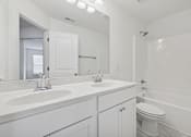 Thumbnail 19 of 27 - A white bathroom with a double sink and a toilet.