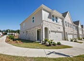 Thumbnail 12 of 25 - Elegant townhome exterior with pristine landscaping and driveway
