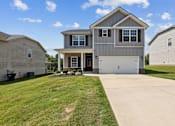 Thumbnail 1 of 44 - A large house with a garage is surrounded by a well-kept lawn.